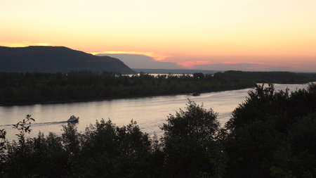 View of the mountains and the river at sunset. View from a hill. Boats float on the river.の写真素材