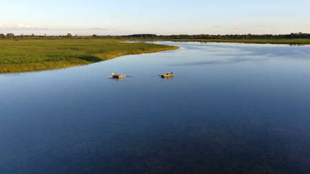 There are two boats floating on the lake. There are green reeds around the lake. View from above.の写真素材