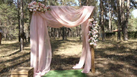 A wedding square arch stands in a pine forest. The wedding decor is decorated with flowers.の写真素材