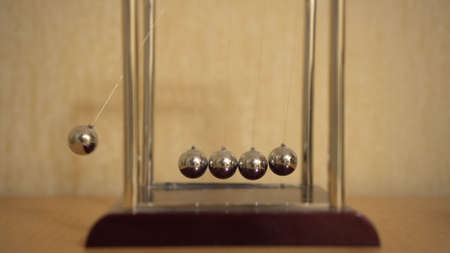 Newtons desk cradle on the table is moving. Balls beat by inertiaの写真素材
