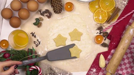 A young woman uses a spatula to pick up a traditional festive Christmas star cookie. View from above.の写真素材