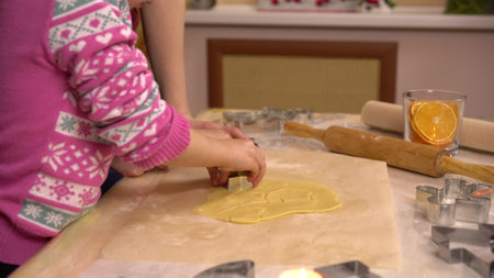 A daughter with a young mother makes gingerbread Christmas cookies in the form of stars. A figurine is placed in the dough.の写真素材