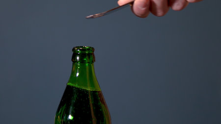 Man opens bottle with fizzy drink with a special opener. Glass bottle with metal lidの写真素材