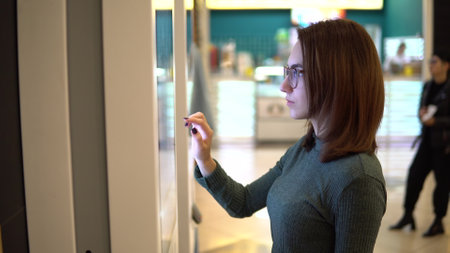 A young woman orders food at the touch terminal in a shopping center. Modern technology. On the food...