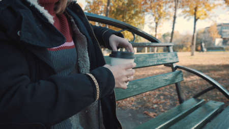 Girl drinks coffee on a bench, close-upの写真素材