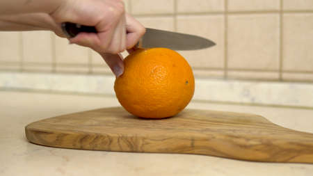 Woman cuts an orange in half. Womans hand close upの写真素材