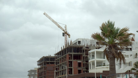 A crane is building a house in a hot country. Overcast. Unfinished houseの写真素材