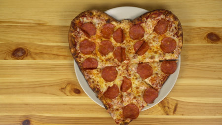 Heart shaped pizza for valentines day. The camera approaches the pizza. View from above.の写真素材