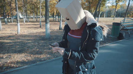 The girl with the package on her head walks with the phone. Girl in a jacketの写真素材