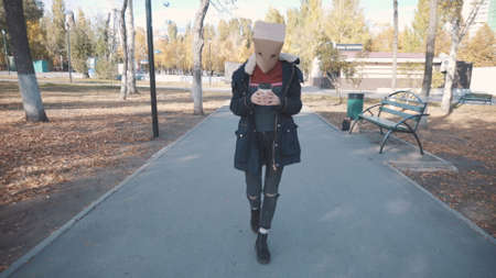 Girl with a package on her head walks with a cup of coffee. Girl in a jacketの写真素材