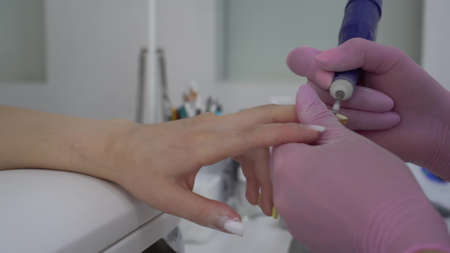 Young Asian woman with glasses in a manicure salon. A manicurist uses a drill machine to remove nails.の写真素材