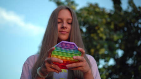 A girl with long hair plays antistress toy in nature.の写真素材