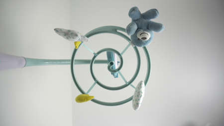 A newborn looks at a childrens mobile with toys lying in a cradle. First-person view from the bottom up.の写真素材