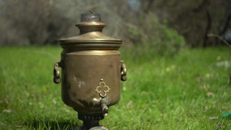 An old bronze samovar stands on the grass at a picnic.の写真素材