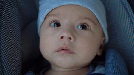 A newborn baby lies in a stroller. Close-up of a childs face.の写真素材