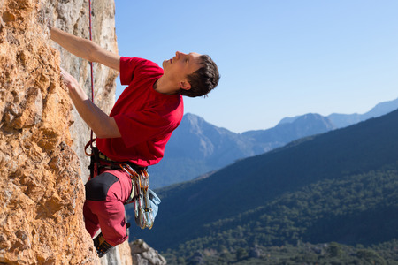 Young male climber hanging by a cliff.の写真素材
