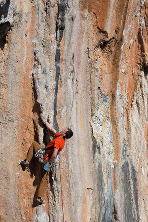 Young male climber hanging by a cliffの写真素材