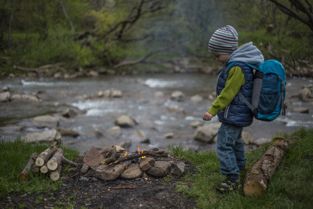 Teenager sitting near a fire in camping and watching map.の写真素材