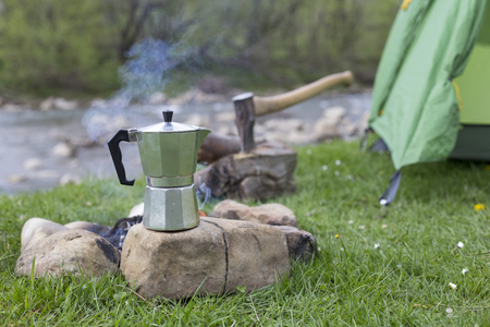 Mug stands on a log near the fire at a campsite.の写真素材