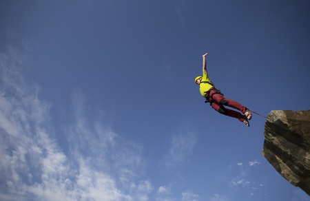 Jump off a cliff into a canyon with a rope.の写真素材