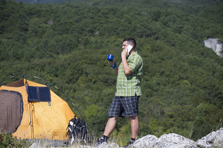 The solar panel attached to the tent. The man sitting next to mobile phone charges from the sun.の写真素材