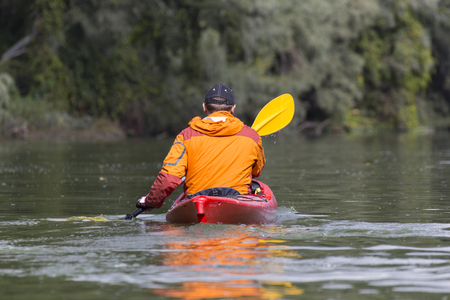 Young man paddling hard the kayak with lots of splashes.の写真素材