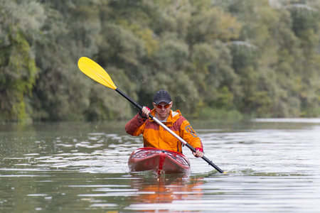 Young man paddling hard the kayak with lots of splashes.の写真素材