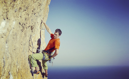 Rock climber reaching for his next hand hold, Joshua Tree National Park.の写真素材