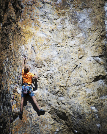 Rock climber reaching for his next hand hold, Joshua Tree National Park.の写真素材