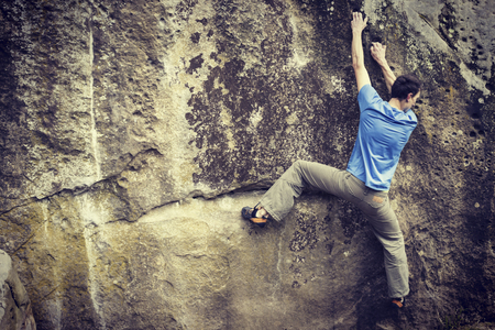 Young man climbing on a limestone wall with wide valley on the backgroundの写真素材