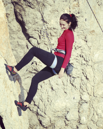 Young man climbing on a limestone wall with wide valley on the backgroundの写真素材