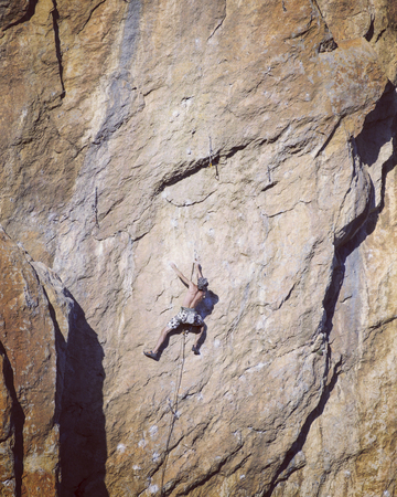 Young man climbing on a limestone wall with wide valley on the backgroundの写真素材