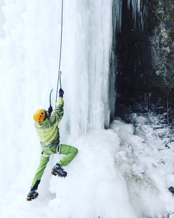 Man climbing a frozen waterfall with ice tool.の写真素材
