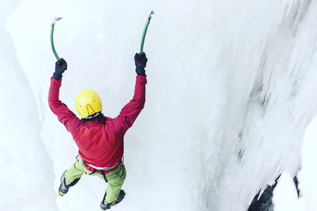 Man climbing a frozen waterfall with ice tool.の写真素材