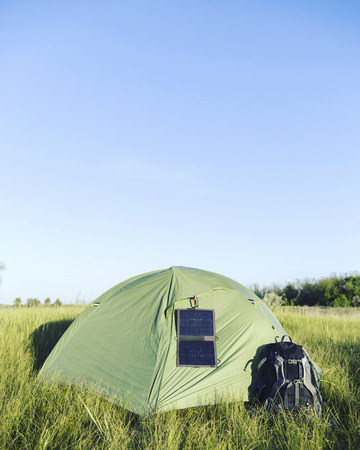 The tent stands in a clearing in the woods solar panel hangs on the tent.の写真素材