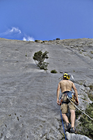 Rock climber reaching for his next hand hold, Joshua Tree National Park.の写真素材