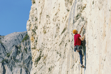 A climber man climbs to the top of a cliff.の写真素材