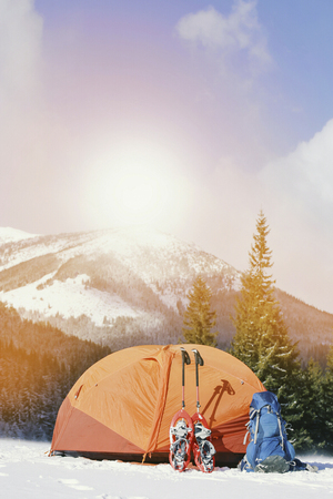 Winter trek in the mountains. The tent stands on the mountainside against the backdrop of the mountains.の写真素材