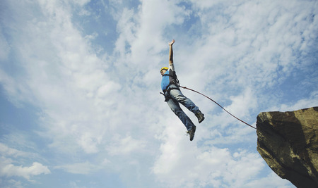 A man jumps into a canyon from a cliff.の写真素材