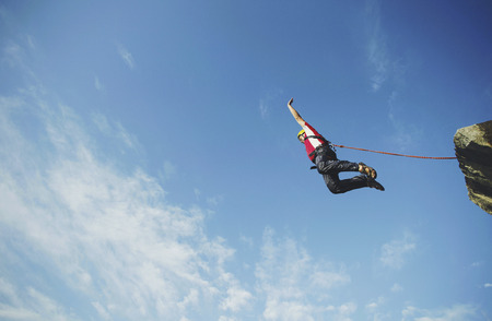 A man jumps into a canyon from a cliff.の写真素材