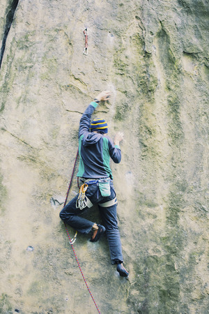 A man climbs the rock on a climbing route.の写真素材