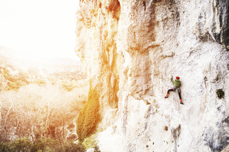 Woman rock climber. Rock climber climbs on a rocky wall. Woman makes hard move.の写真素材