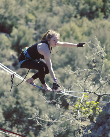 Highliner on a rope. Highline on a background of mountains. Extreme sport on the nature. Balancing on the sling. Equilibrium at altitude.の写真素材