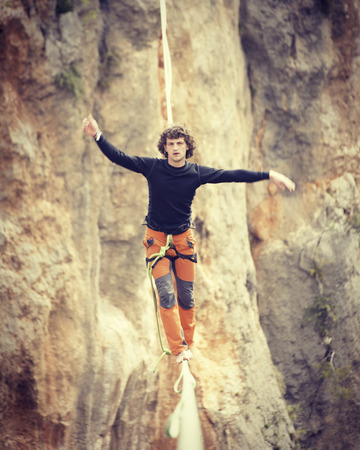 Highliner on a rope. Highline on a background of mountains. Extreme sport on the nature. Balancing on the sling. Equilibrium at altitude.の写真素材