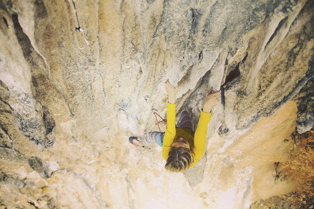 The girl climbs the rock. Fitness in nature and rock climbing. The climber climbs up.の写真素材