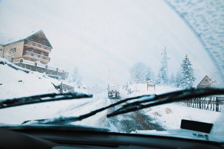 snowblower clears a snowy road, heavy snowfall, view from a car window.