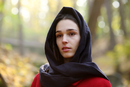 Girl in black scarf walks in autumn park.の写真素材