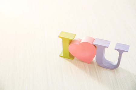 Wooden colored letters - I love you, on a light wooden background with a solar flareの写真素材