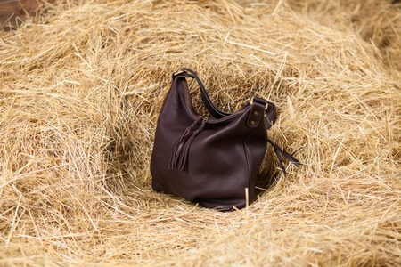 leather bag on a background of yellow hayの写真素材