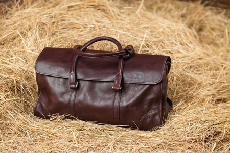 leather bag on a background of yellow hayの写真素材